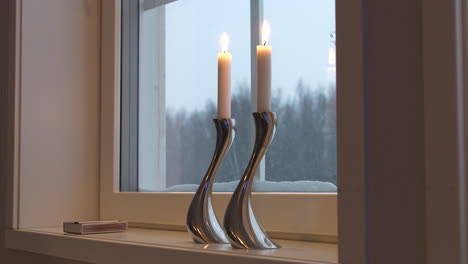 Static-view-of-silver-design-candlesticks-in-windowsill-in-winter