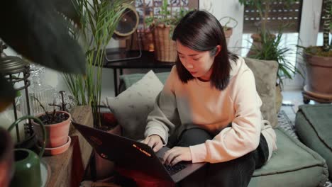 Asian-black-haired-woman-working-on-telecommuting-moving-her-fingers-quick-over-the-keypad-since-she-is-working-from-home-in-COVID-19-pandemy