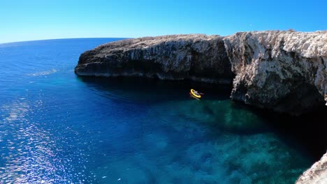 Wide-angle-view-and-panoramic-view-over-a-sea-cave-with-a-kayaker-exploring-the-coast-line-on-a-beautiful-sunny-day,-Vis-island,-Adriatic-Sea,-Croatia