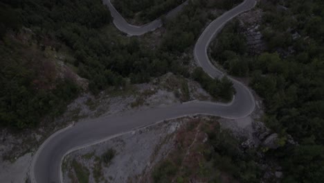 drone-video-of-"revealing-front-shot-ending-front-shot",-about-two-motorcycles-and-some-cars-on-the-sh21-of-the-Theth-mountain-pass-in-albania,-the-Valbona-valley-in-view-of-Mount-Korab