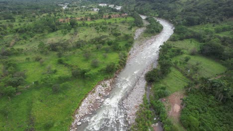 Luftwagen-In-Einem-Felsigen-Fluss,-Der-In-Wiese-Und-Wald-Fließt,-Hügel-Im-Hintergrund,-General-Viejo,-Costa-Rica