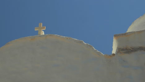 Detailaufnahme-Eines-Katholischen-Kreuzes-Auf-Der-Spitze-Eines-Typischen-Hauses-In-Griechenland,-Im-Herzen-Eines-Kleinen-Dorfes-Am-Rande-Der-Küste