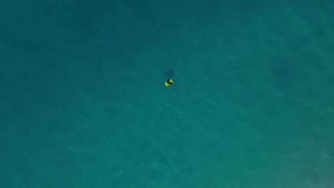 Bodyboarder-alone-in-ocean-waiting-on-waves,-top-down-drone-view