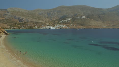 Wide-shot-of-a-very-beautiful-sandy-beach-and-turquoise-sea-in-a-paradise-bay,-some-swimmers-are-bathing,-Egliali-Greece,-Cyclades-Islands