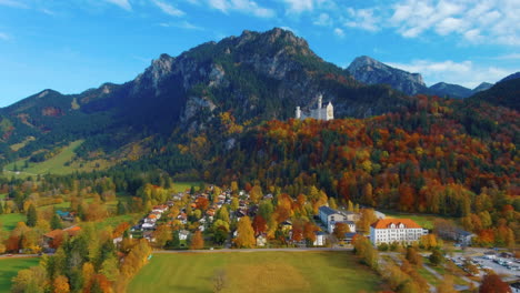 Entspannender-Blick-Auf-Die-Drohne,-Die-Am-Nachmittag-In-Der-Nähe-Des-Schlosses-Neuschwanstein-In-Deutschland,-Europa,-Weitblick-über-Autos-Und-Bäume-In-Einem-Malerischen-Herbstfeld-Gleitet