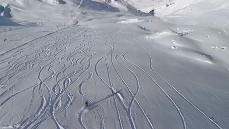 Aerial-drone-view-over-a-skier,-slalom-skiing-on-snowy-slopes-in-sunny-Kaunertal,-Austria