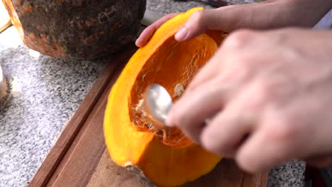 Removing-Pumpkin-Pulp-And-Seeds-With-A-Spoon-In-The-Kitchen