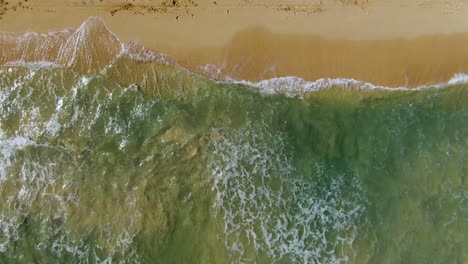 birds-eye-view-drone-descending-down-onto-ocean-waves-crashing-on-sandy-hawaiian-beach