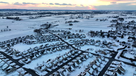 Suburban-homes-and-rural-farm-fields-in-winter-snow-at-colorful-sunset