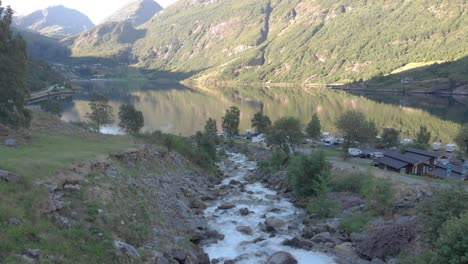 Die-Drohne-Folgt-Einem-Wasserfall,-Der-Zu-Einem-Fluss-Wird-Und-In-Den-Geirangerfjord-Mündet