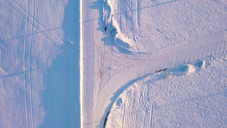 Rural-road-intersection-under-thick-snow-layer,-aerial-top-down-ascend-shot
