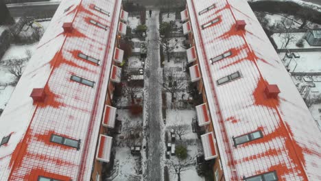 Aerial-of-contrasting-red-brick-roofs-covered-with-snow,-on-snowy-gray-streets