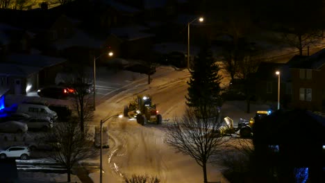 High-angle-view-of-two-Snow-plow-tractors-removing-snow-from-the-road-with-no-traffic-movement-at-night
