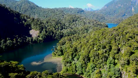 Aerial-dolly-in-of-turquoise-lake-between-Andean-mountains-with-dense-green-rain-forest,-Huerquehue-National-Park,-Chile