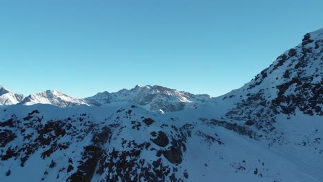 Aerial-view-over-mountains,-revealing-snowy-peaks,-sunny,-winter-day-in-Austria---rising,-drone-shot