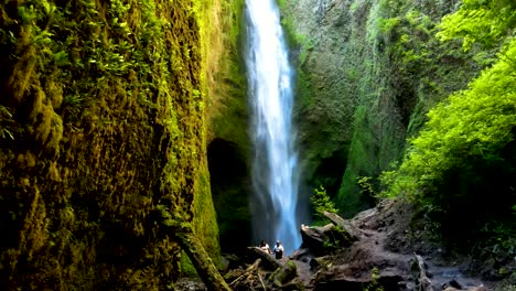 Dolly-out-of-hidden-Mili-Mili-waterfall-streaming-into-natural-pool-surrounded-by-dense-green-vegetation,-Coñaripe,-Chile