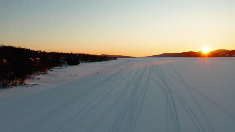 Luftfliegen-über-Einem-Zugefrorenen-See,-Während-Menschen-Auf-Eis-Und-Schnee-Spielen-Und-Wandern