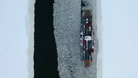 Top-down-aerial-view-of-two-car-ferries-passing-each-other-as-they-cross-an-ice-covered-river