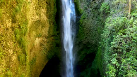 Dolly-Aus-Verstecktem,-Nebligem-Wasserfall,-Versteckt-Zwischen-Mit-Vegetation-Bedeckten-Wänden,-Lastwagen-Links,-Der-Zu-Dichten-Wäldern-Führt