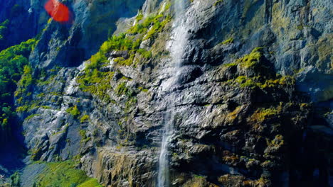 Calming-hovering-drone-shot-of-iconic-waterfall-flowing-at-noon-in-Lauterbrunnen,-Switzerland,-Europe,-wide-view