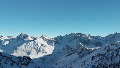 Luftaufnahme-Mit-Blick-Auf-Felsige-Bergketten,-Verschneite-Winterlandschaft---Rückseite,-Drohnenaufnahme
