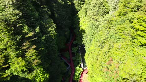 Aerial-dolly-in-over-wood-red-runway-in-Termas-Geometricas-hot-spring-complex,-surrounded-by-forest,-Coñaripe,-Chile