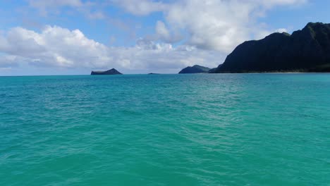 Flotando-Lentamente-En-El-Océano-Hawaiano-Hacia-La-Costa-Con-Mini-Islas-En-La-Distancia