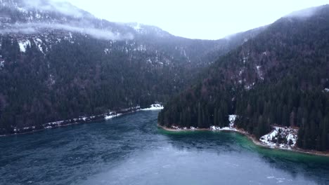 Luftaufnahme-Eines-Atemberaubenden-Zugefrorenen-Sees-Unter-Den-Alpen-Mit-Den-Inseln-Im-Schnee