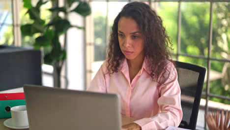 Latin-woman-working-with-hand-holding-card-on-working-space-at-home