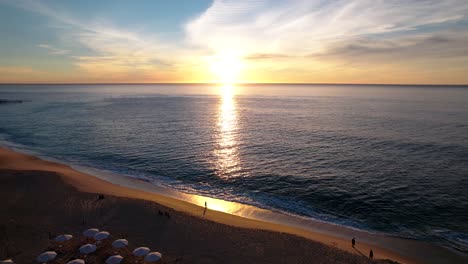 Aerial-of-a-Sunrise-over-a-Cabo-beach-and-a-calm-sea-with-vibrant-colors