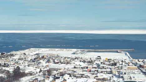 Aerial-View-Over-Snow-Winter-Town-Of-Omu-With-Sea-of-Okhotsk-In-Horizon-In-Hokaddio