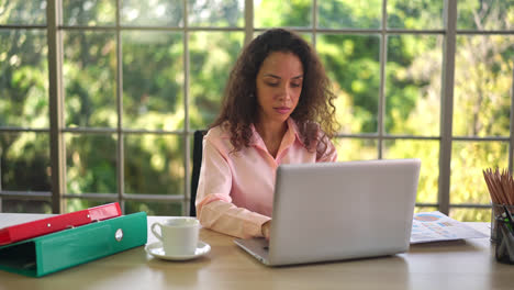 Latin-woman-working-with-hand-holding-card-on-working-space-at-home