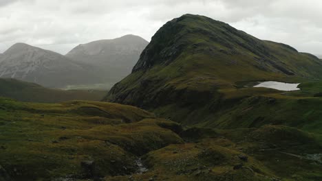 Giant-rocks-between-small-streams-and-green-landscape-with-in-the-background-Bla-bheinn-all-originated-during-the-glacial-period-on-Isle-of-Skye