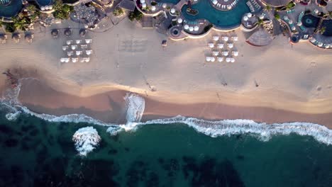 A-resort-beach-in-a-tropical-paradise-with-swimming-pools-and-cabanas---straight-down-ascending-aerial-view