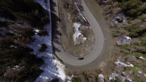Van-going-around-switchback-corner-in-the-mountains-aerial-shot-from-above