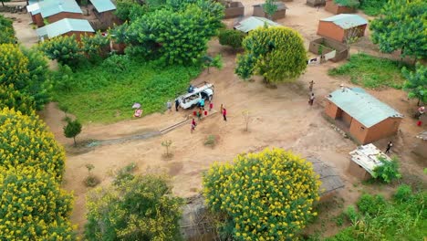 Drone-flying-over-a-village-with-a-car-driving-towards-it