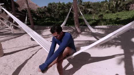 Hispanic-Male-Seating-on-a-Hammock-While-Taking-His-Water-Shoes-Off