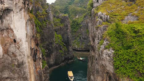Wang-Long-Bay-hidden-behind-the-enormously-steep-rock-walls-which-are-partly-covered-with-green-vegetation-while-a-boat-sails-across-the-clear-bay
