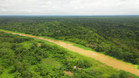 Wide-rotating-drone-shot-of-the-amazon-river-with-a-small-boat-going-down-the-river-with-the-Amazon-rainforest-surrounding-on-all-sides-in-Peru