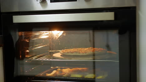 Someone-places-a-pizza-into-an-oven-onto-a-pizza-stone