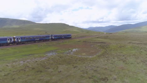 Aerial-tracking-shot-of-a-commuter-train-heading-across-Rannoch-Moor
