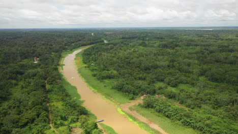 Breite-Rotierende-Drohnenaufnahme-Mit-Einem-Boot,-Das-Den-Amazonas-Und-Den-Regenwald-Um-Den-Fluss-In-Peru-Hinunterfährt