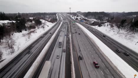Tracking-Aerial-Flyover-of-Busy-Winter-Highway-with-blowing-Snow-and-transport-trucks-in-Scarborough-Toronto-East-401,-Overcast-Day