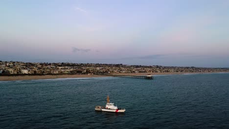 Sailing-Coastguard-Boat-On-Tranquil-Water-Of-The-Pacific-Ocean-Near-Manhattan-Beach-Pier-In-California,-USA