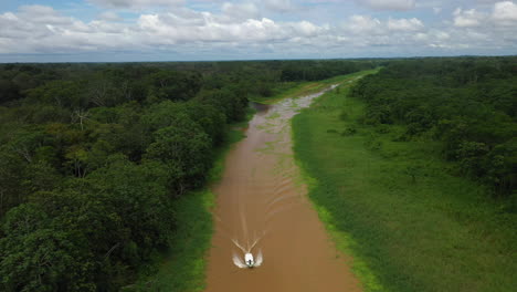 Wide-rising-drone-shot-with-a-boat-coming-down-the-Amazon-river-and-the-rainforest-surrounding-the-river-in-Peru