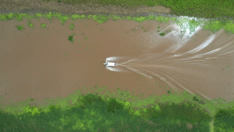 Cinematic-downward-angle-drone-shot-with-a-boat-with-wake-on-the-Amazon-river-and-the-rainforest-surrounding-the-river-in-Peru
