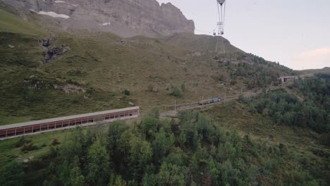shot-from-inside-a-mountain-cableway-looking-out-over-a-moving-mountain-train-in-Switzerland-in-4k