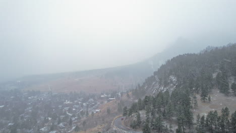 Drone-Aerial-Footage-Over-Snowcapped-Pine-Tree-Hillside-Road-near-Flatirons-Mountain-in-Boulder-Colorado-USA-During-Foggy-Snowstorm-Blizzard