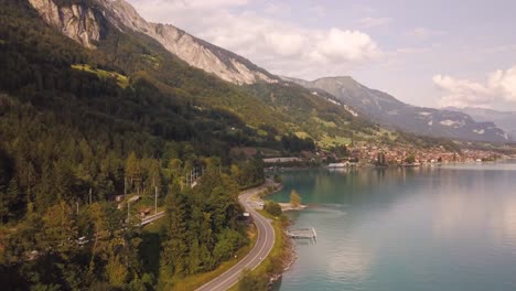 Tiro-De-Drone-Volando-Cerca-De-Una-Carretera-Al-Lado-Del-Lago-De-Montaña-De-Luzerne-En-Suiza-4k