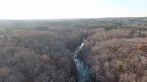 Aerial-Over-North-Carolina-Eno-River-Through-Leafless-Forest-In-Fall